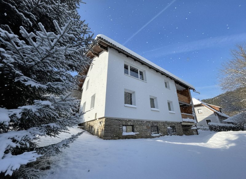 A White Pearl Apartment épülete télen, friss hóban, kék ég alatt